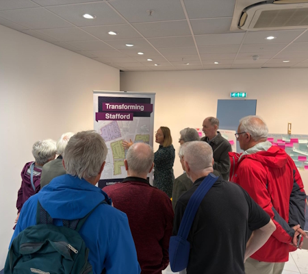 People looking at a Transforming Stafford Board